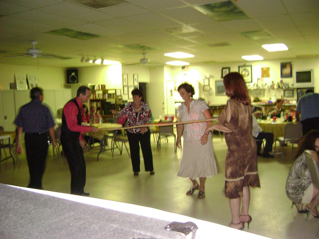 Jimmy Rivera (Left) and Rosie Pagan (Right) holding the limbo stick for Lucy Santa (Center). Gladys Piñeiro is waiting for her turn